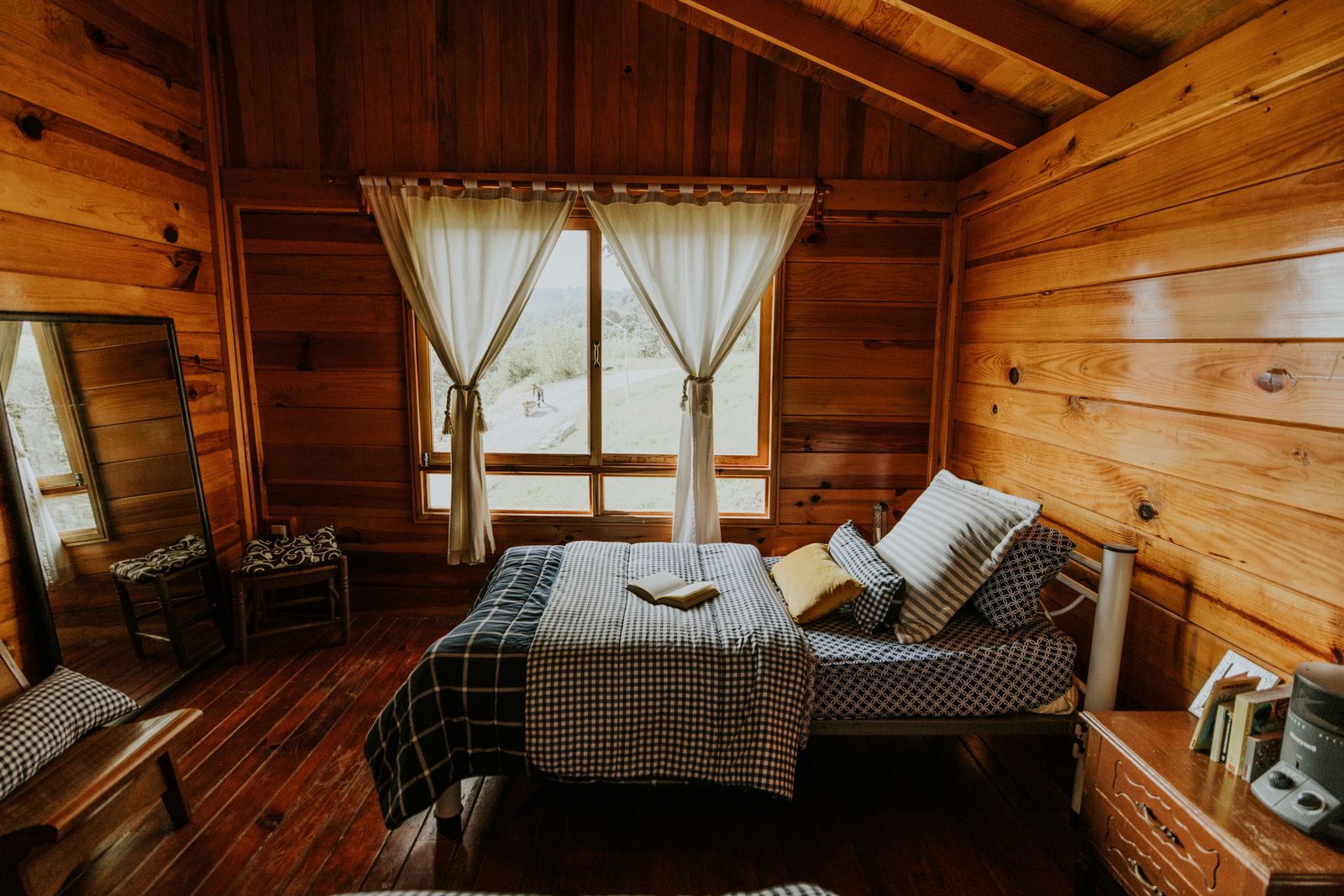 A bright, well-staged cabin bedroom with a scenic view — the kind of inviting space that earns direct bookings