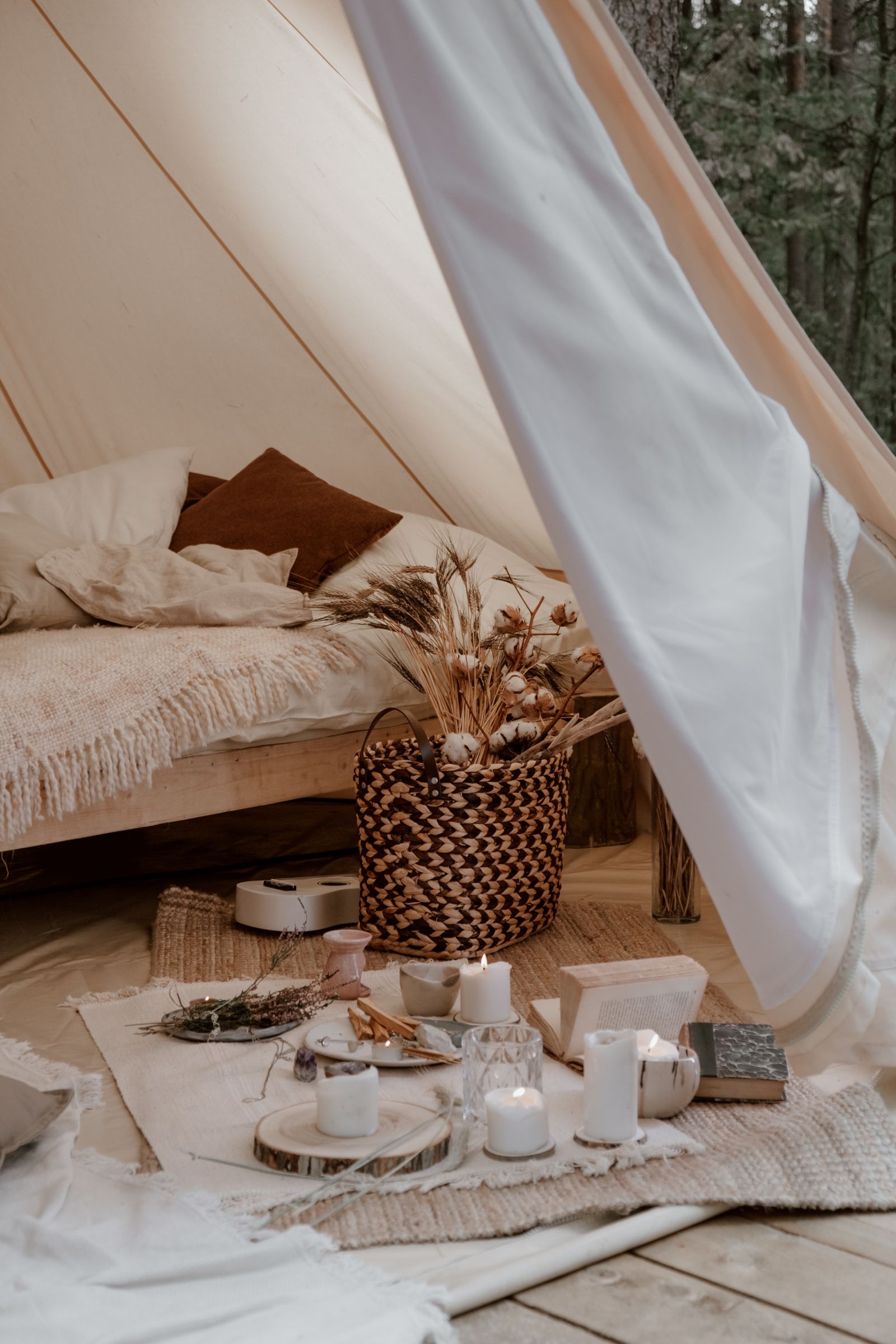 A warm, thoughtfully styled glamping interior with candles and string lights at dusk