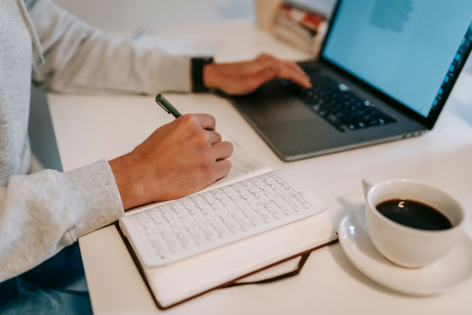 A cozy windowside desk with a laptop and coffee, set up for writing guest emails