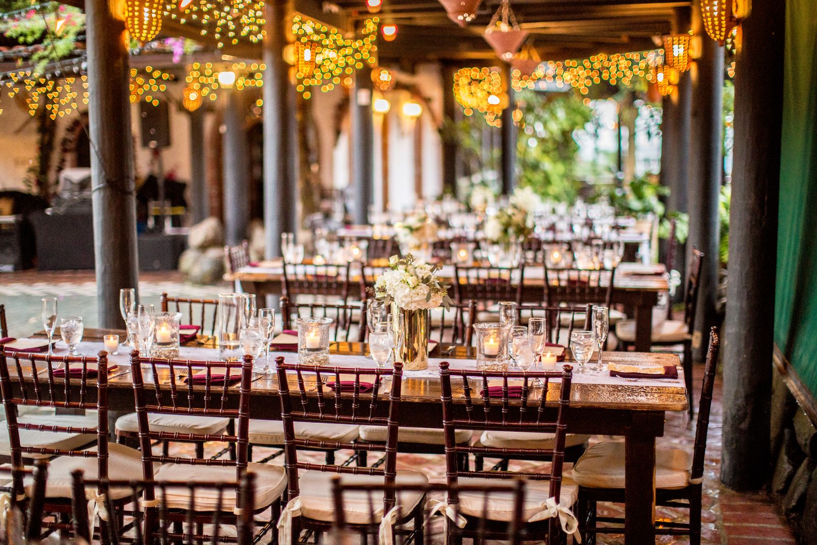 An outdoor event table glowing under warm bistro lights at dusk