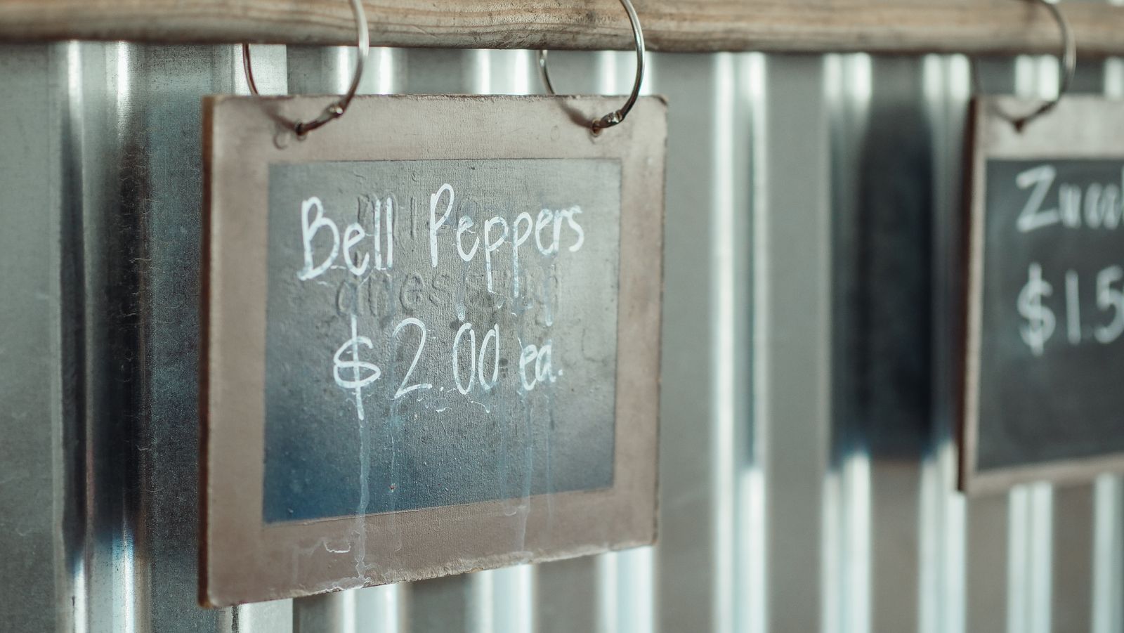 A chalkboard sign showing the price of fresh peppers at a farm market