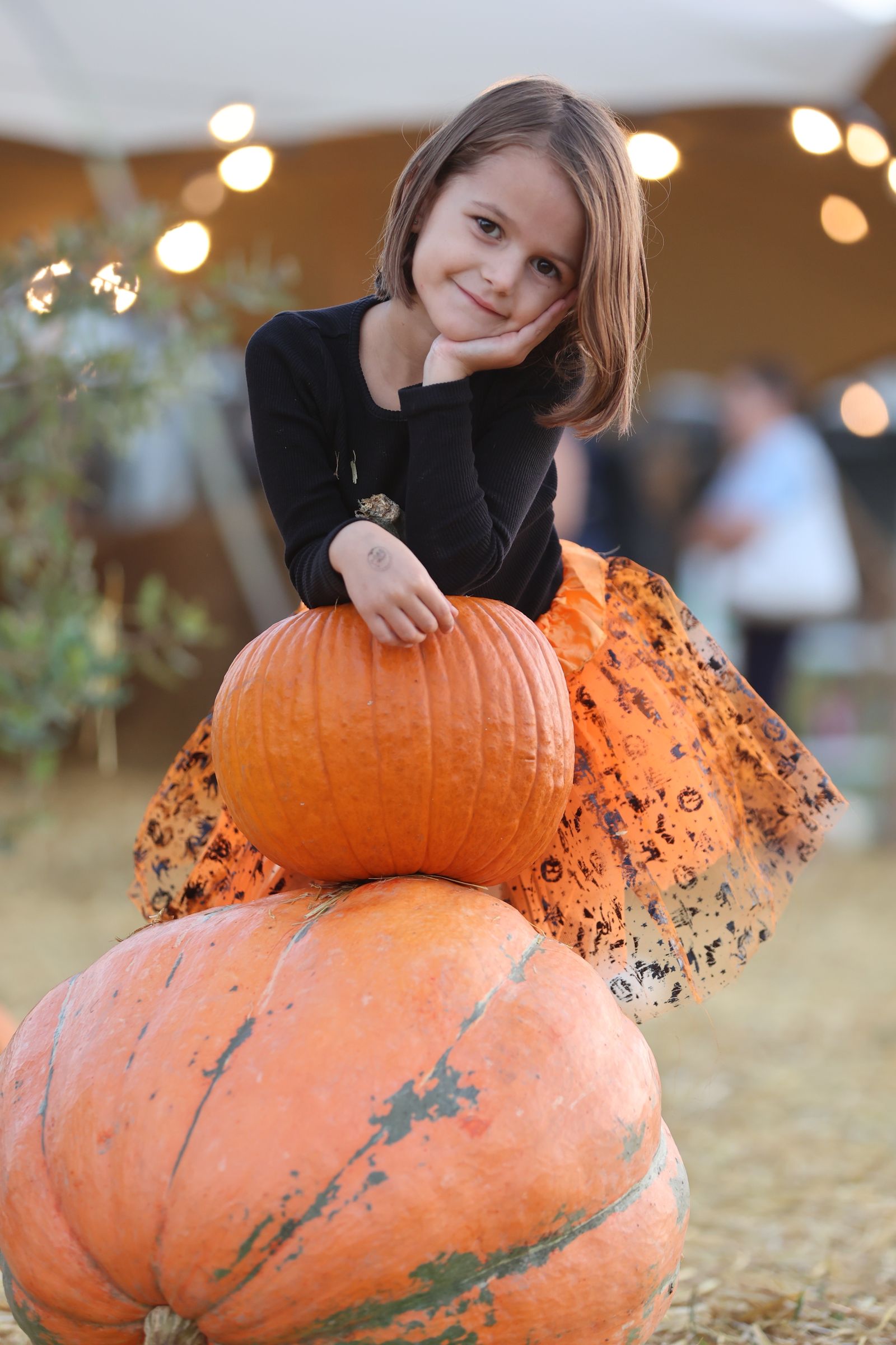 A young visitor posing with pumpkins at the farm