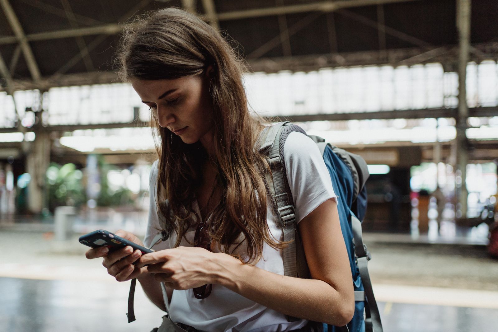 A traveler checking her smartphone at a train station while on a trip